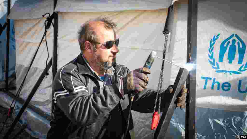 Workers install extra protection for the tents as part of efforts to prepare for the winter. (J. Owens for VOA)