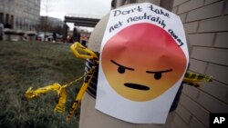 FILE - A sign with an emoji that reads "Don't take net neutrality away" is posted outside the Federal Communications Commission (FCC), in Washington, Dec. 14, 2017.