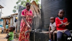 Judith Andeka, veuve et mère de cinq enfants, va chercher de l'eau avec un seau dans le bidonville de Kibera, à Nairobi, au Kenya, le 10 avril 2020. (AP Photo/Brian Inganga)