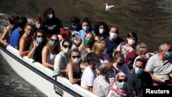 People wear protective face masks on a boat trip on a canal in central Bruges, Belgium, Aug. 5, 2020. 