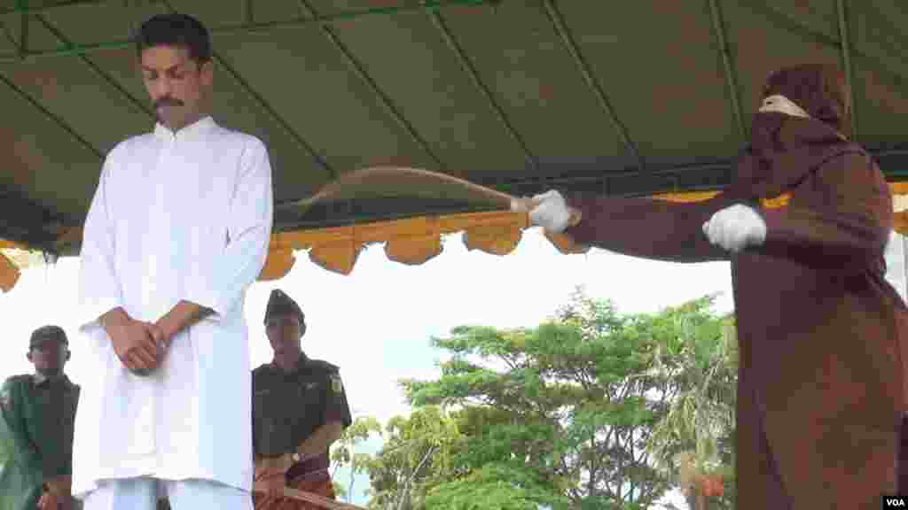 A prosecutor takes the cane to a man convicted of playing a card game for money, Dec. 5, 2014. (Maimun Saleh/VOA)