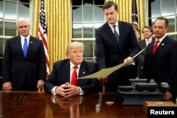 FILE - White House Staff Secretary Rob Porter gives U.S. President Donald Trump, flanked by Vice President Mike Pence, left, and Chief of Staff Reince Priebus, right, the document to confirm Secretary of Defense James Mattis.