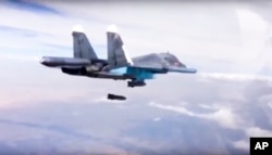 FILE - In this Dec. 9, 2015 file photo made from video footage provided by the Russian Defense Ministry, a Russian Su-34 bomber drops bombs on a target.