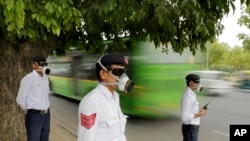 Polusi India mengenakan masker sambil mengatur lalu lintas di New Delhi, India.