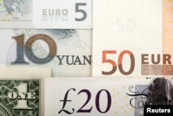 FILE - The Chinese yuan, shown Jan. 25, 2011, with the U.S. dollar, euro and British pound, is gradually moving to become a more market-oriented currency, and its international profile is growing.