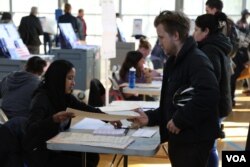 Voter gets his ballot before voting in presidential election at polling station in New York City, Nov. 8, 2016. (Photo: R. Taylor / VOA)