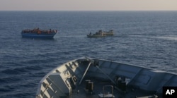FILE - In this photo released by the Italian Navy Wednesday, April 9, 2014, Italian Navy's dingies approach a boat carrying migrants along the Mediterranean sea, off the Sicilian island of Lampedusa