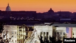 The damaged area of the Pentagon building, Islamic extremists flew a plane into it September 11, is seen in the early morning at sunrise with the U.S. Capitol Building in the background, September 16, 2001.