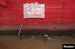 A baby shower sign hands on a wall at the home of Carlos Rojas after rivers breached their banks due to torrential rains, causing flooding and widespread destruction in Carapongo Huachipa, Lima, Peru, March 21, 2017.