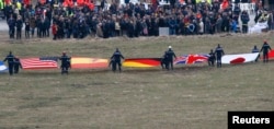 Flags representing some of the nationalities of the victims are seen as family members and relatives gather near the crash site of an Airbus A320 in the French Alps, March 26, 2015. The co-pilot of the Germanwings airliner that crashed in the French Alps