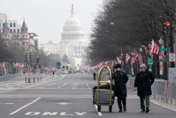 Danish Rozario, left, of Silver Spring, Md., wheels baggage down Pennsylvania Avenue for a guest at the Trump Hotel in Washington, Friday, Jan. 15, 2021, ahead of the inauguration of Joe Biden. (AP Photo/Susan Walsh)