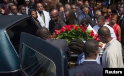 Lesley McSpadden (R, in red) watches as the casket containing the body of her son Michael Brown lifted into a hearse after his funeral services at Friendly Temple Missionary Baptist Church, St. Louis, Missouri, August 25, 2014.