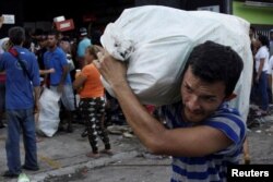 People carry goods taken from a food store in La Fria, Venezuela, Dec. 17, 2016.