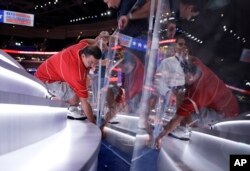 A worker, who declined to give his name, helps install an acrylic barrier in front of the stage before the third day session of the Republican National Convention, in Cleveland, July 20, 2016.