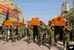 FILE - Members of the Shi'ite group Asaib Ahl al-Haq, or "League of the Righteous," carry coffins of colleagues killed while helping Iraqi security forces battle Islamic State group in Beiji, at a funeral in Najaf, 160 kilometers south of Baghdad, Oct. 18, 2015.