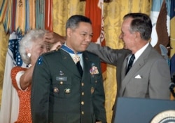 FILE - President George Bush loans his glasses to first lady Barbara Bush as she pins a Medal of Freedom on Gen. Colin Powell, chairman of the Joint Chiefs of Staff, during a White House ceremony, July 3, 1991.