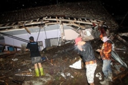 Warga dan tim penyelamat melakukan pencarian korban di tengah reruntuhan bangunan pasca banjir bandang yang sejauh ini dilaporkan hilang 11 orang, di Malang, Jawa Timur pada 4 November 2021. (Foto: AFP)