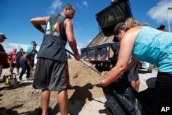 Giovanni Rivera, left, and Nuvia Rivera fill a sandbag, Sept. 12, 2018, in Virginia Beach, Va., as Hurricane Florence moves towards the eastern shore.