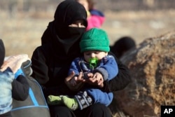 A Syrian woman and a child, who were evacuated from the Syrian city of Aleppo during the ceasefire, arrive at a refugee camp in Rashidin, near Idlib, Syria, Dec. 19, 2016.