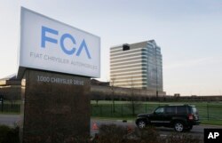 FILE - In this May 6, 2014, photo, a vehicle moves past a sign outside Fiat Chrysler Automobiles world headquarters in Auburn Hills, Michigan.