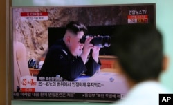FILE - A man watches a TV screen showing a local news program reporting about North Korea's missile firing with an image of North Korean leader Kim Jong Un with a pair of binoculars, at Seoul Train Station in Seoul, South Korea, July 5, 2017.