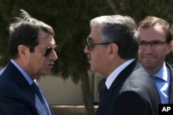 FILE - Cypriot President Nicos Anastasiades, left, and breakaway Turkish Cypriot leader Mustafa Akinci, right, talk at the disused Nicosia airport inside a United Nations controlled buffer zone in this divided island of Cyprus, Sept. 14 2016.