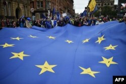 FILE - Protesters carry a giant EU flag during an anti-Brexit march in Manchester, Oct. 1, 2017.