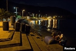 Men carry containers filled with gasoline in the bay of Rio Caribe, in the eastern state of Sucre, Venezuela, Oct. 30, 2015.