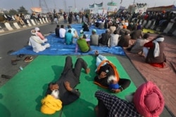 Petani India mendengarkan pembicara saat mereka memblokir jalan raya saat melakukan aksi protes terhadap undang-undang pertanian baru di New Delhi, India, Senin, 21 Desember 2020.