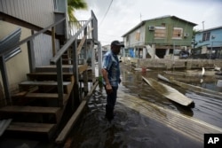 Juana Matos resident Hector Rosa walks through a flooded area after the passing of Hurricane Maria, in Puerto Rico, Wednesday, September 27, 2017.