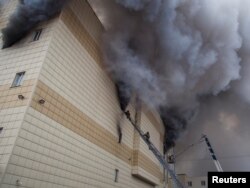 Members of the Emergency Situations Ministry work to extinguish a fire in a shopping mall in the Siberian city of Kemerovo, Russia.