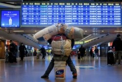Seorang pelancong terlihat dengan barang-barangnya di stasiun kereta api, di tengah pandemi COVID-19, di Beijing, China 13 Januari 2021. (REUTERS / Thomas Peter)