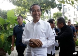 Incumbent Indonesian President Joko Widodo, center, smiles upon arriving for a meeting with leaders of his coalition parties in Jakarta, April 18, 2019.