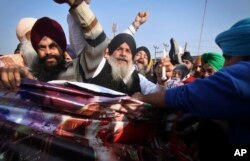 FILE - Sikh protesters hold a poster of Indian religious sect Dera Sacha Sauda chief Baba Ram Rahim Singh's debut film “MSG: The Messenger of God” in Jammu, India, Feb. 13, 2015.