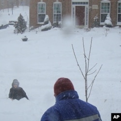 A man shovels snow while a child plays in his yard in freezing temperatures, Springfield, Virginia, 31 Jan 2010