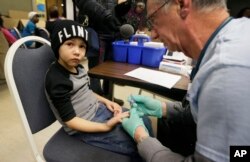 FILE - A nurse draws a blood sample from a student at Eisenhower Elementary School in Flint, Michigan, Jan. 26, 2016. Students at the school were being tested for lead after the metal was found in the city's drinking water.