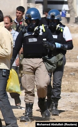 A U.N. chemical weapons expert wearing a gas mask carries samples collected from one of the sites of an alleged chemical weapons attack in the Ain Tarma neighbourhood of Damascus August 28, 2013. U.N. chemical weapons experts investigating an apparent gas