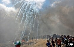 Palestinians run for cover from tear gas fired by Israeli forces near the border between the Gaza strip and Israel east of Gaza City, May 14, 2018, as Palestinians protest over the inauguration of the U.S. embassy following its controversial move to Jerusalem.