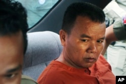 FILE - Yem Chrin, an unlicensed medical practitioner, is escorted by prison guards in Battambang province, northwest of Phnom Penh, Cambodia, Dec. 3, 2015.