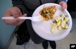 In this Thursday, March 15, 2018, photo, a patient in recovery holds up a plate of food created by registered dietitian Tracey Burg.