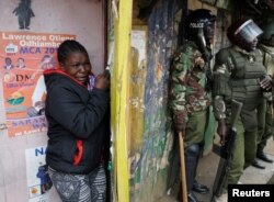 A woman cries as she takes cover during clashes between supporters of opposition leader Raila Odinga and policemen in Kibera slum, Nairobi, Kenya, Aug. 12, 2017.