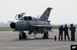 In this April 6, 2016 photo, ground crew stands on the tarmac by a MiG 21 fighter jet, near Belgrade, Serbia. Russian President Vladimir Putin has reportedly promised to sign off on a delivery of six MiG-29 fighter jets to Serbia.