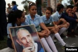 A student holds an image of Cuba's late President Fidel Castro while awaiting the caravan carrying Castro's ashes in Camaguey, Cuba, Dec. 1, 2016.