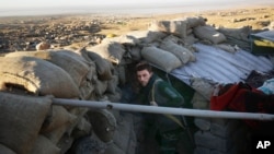 FILE - A Kurdish peshmerga fighter pauses during an operation to retake the northern Iraqi town of Sinjar, Nov. 12, 2015.