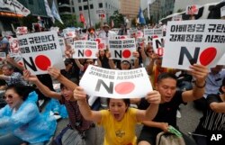 South Korean protesters shout slogans during a rally to denounce Japan's new trade restrictions on South Korea in front of the Japanese embassy in Seoul, South Korea, Saturday, Aug. 3, 2019. (AP Photo/Ahn Young-joon)