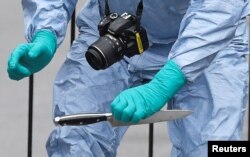 FILE - A forensic investigator recovers a knife after man was arrested on Whitehall in Westminster, central London, April 27, 2017.