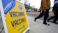 A sign, in Spanish and English, points the way to a vaccination clinic at City of Lawrence's "The Center," which serves seniors, families and the community, in Lawrence, Mass., Dec. 29, 2021.