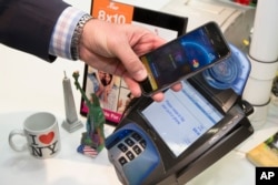 FILE - A customer makes a purchase with a MasterCard using Apple Pay on the iPhone 6 at Walgreens in New York's Times Square, Oct. 20, 2014.
