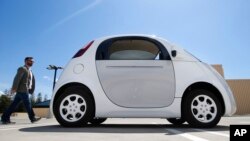 In this May 13, 2015 photo, a reporter walks toward Google's new self-driving prototype car during a demonstration at the Google campus in Mountain View, Calif.