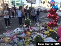 Route 91 Festival goers, tourists and residents of Las Vegas placed candles, flowers, banners and photos of their loved ones at the shrine on the median just across the street from shooting site at the country music festival.